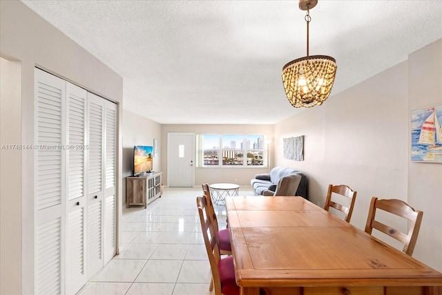 dining area featuring a textured ceiling, a notable chandelier, and light tile patterned floors