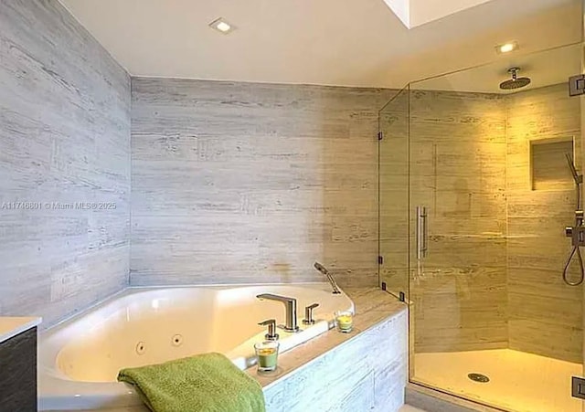 full bath featuring a jetted tub, a shower stall, and tile walls