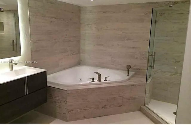 bathroom featuring a jetted tub, a shower stall, vanity, and tile walls