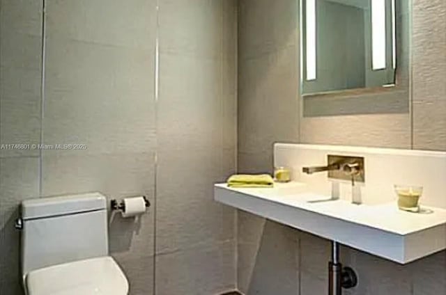 bathroom featuring tile walls and toilet