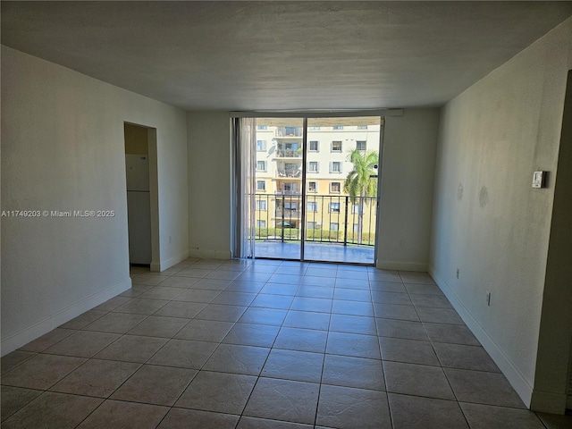 unfurnished room featuring baseboards, light tile patterned flooring, and floor to ceiling windows