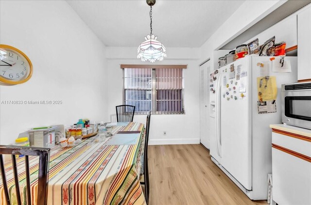 500 SW 130th Ter Unit 407A, Pembroke Pines, FL 33027 - kitchen with white fridge with ice dispenser, light wood-type flooring, decorative light fixtures, stainless steel microwave, and baseboards