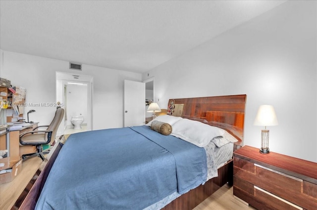 bedroom with light wood-style flooring and ensuite bath