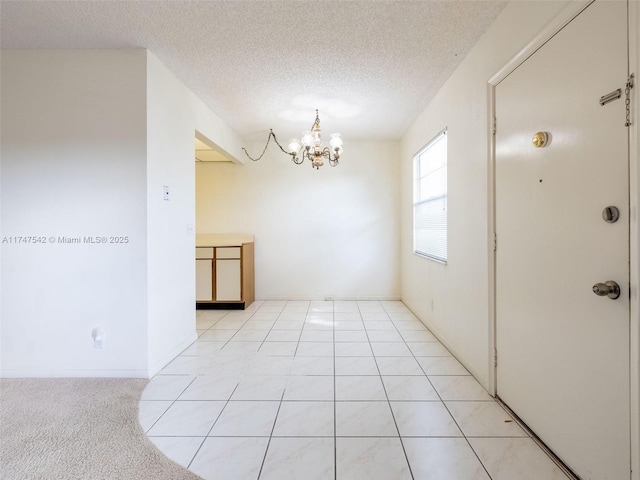 unfurnished room with a chandelier, a textured ceiling, and light colored carpet