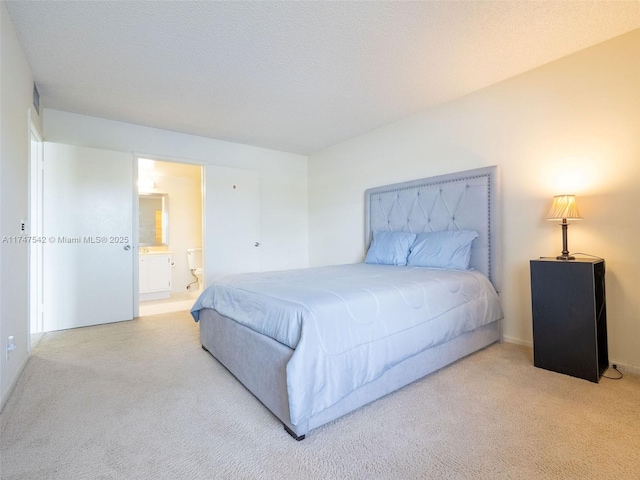 carpeted bedroom featuring a textured ceiling and ensuite bath