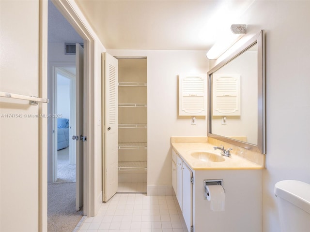 bathroom with tile patterned flooring, toilet, visible vents, vanity, and a closet