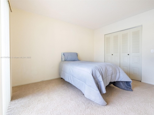 bedroom with a closet, light colored carpet, and baseboards