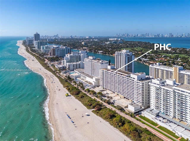 drone / aerial view with a water view, a view of the beach, and a city view