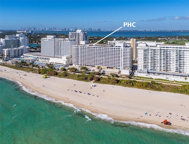 drone / aerial view featuring a city view, a water view, and a beach view