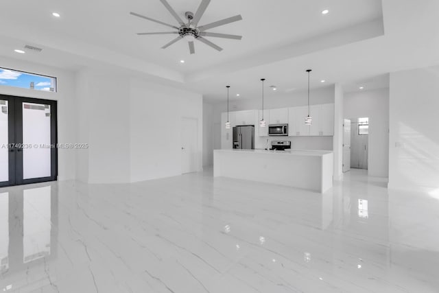 unfurnished living room with a tray ceiling, french doors, visible vents, and recessed lighting