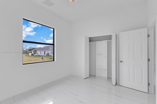 unfurnished bedroom with marble finish floor, a closet, visible vents, and baseboards