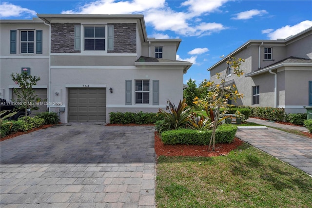 view of front of property featuring decorative driveway, stone siding, an attached garage, and stucco siding