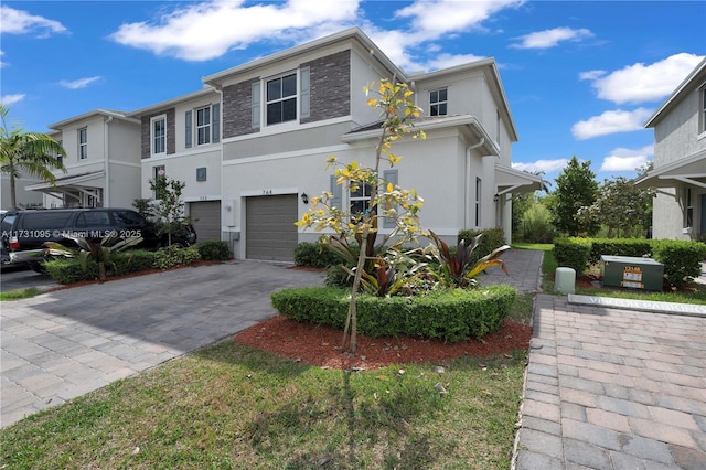 view of front of house featuring decorative driveway, an attached garage, and stucco siding