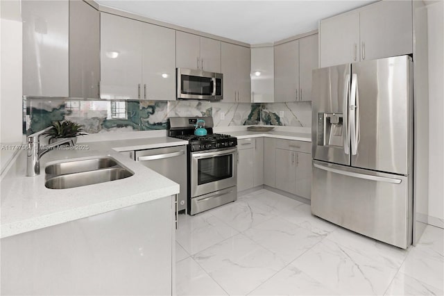 kitchen featuring a sink, marble finish floor, light countertops, appliances with stainless steel finishes, and tasteful backsplash