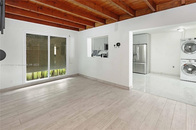 spare room featuring stacked washer and clothes dryer, light wood-style floors, wooden ceiling, beamed ceiling, and baseboards