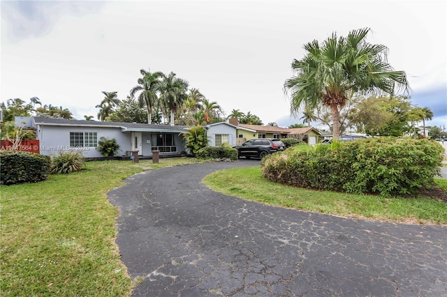 single story home featuring aphalt driveway, a front yard, and stucco siding