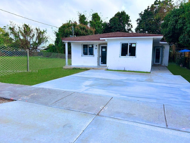 ranch-style house featuring fence, a front lawn, and stucco siding