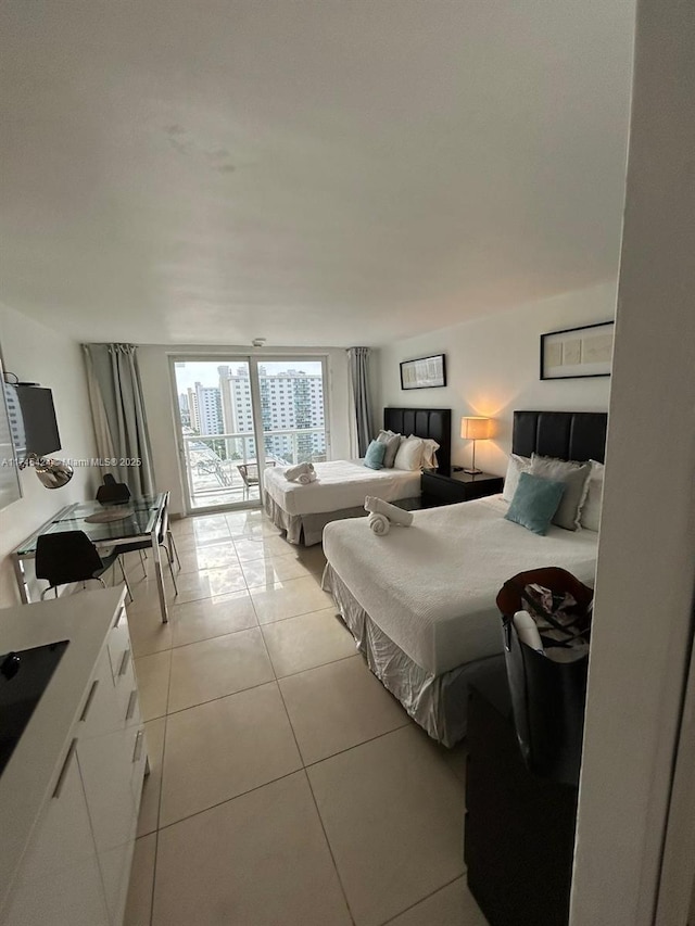 bedroom with light tile patterned floors, a wall of windows, and access to exterior