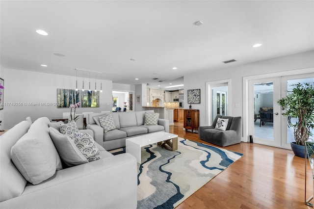 living room featuring recessed lighting, french doors, visible vents, and light wood-style flooring