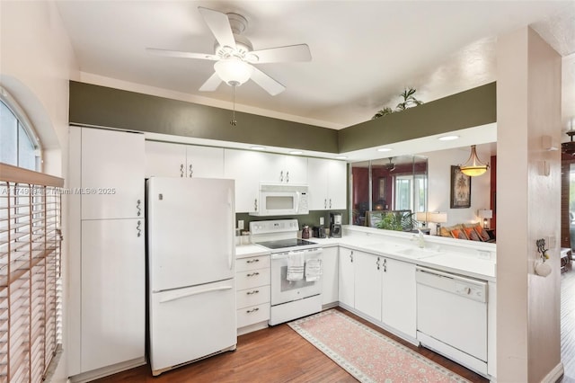 kitchen with light countertops, white appliances, wood finished floors, and white cabinetry