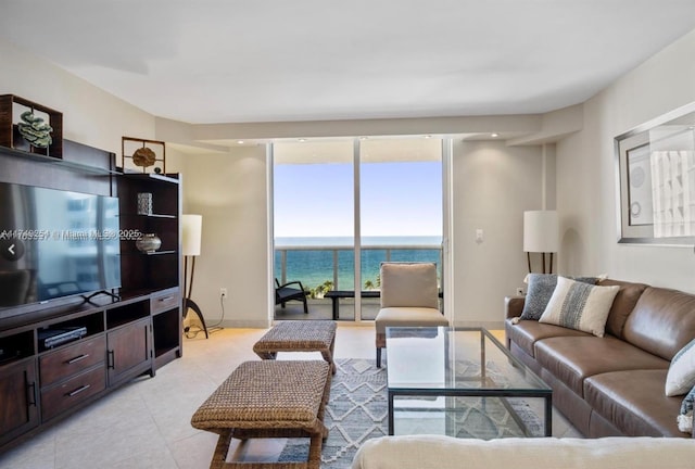 living room featuring a wall of windows, a water view, baseboards, and light tile patterned floors