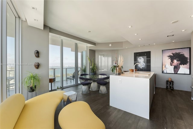 kitchen with dark wood finished floors, recessed lighting, a water view, expansive windows, and a sink