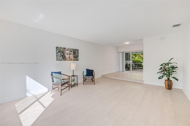 living area featuring light wood-style flooring and visible vents