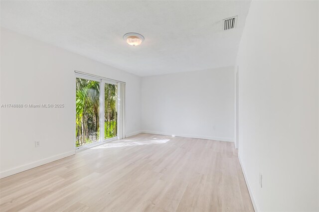 unfurnished room with light wood-type flooring, visible vents, and baseboards