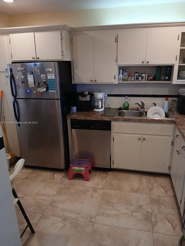 kitchen featuring light tile patterned floors, stainless steel appliances, open shelves, white cabinets, and a sink