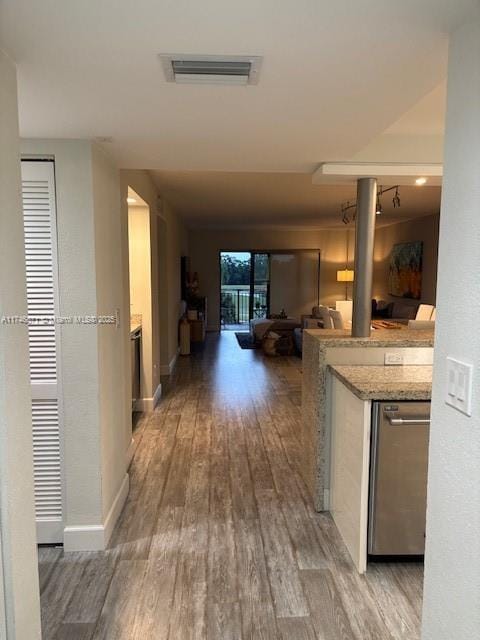 hallway featuring light wood finished floors, visible vents, and baseboards