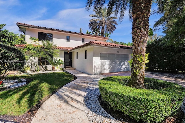 mediterranean / spanish-style home with a garage, driveway, a tile roof, and stucco siding