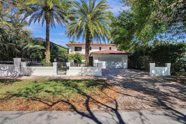 mediterranean / spanish-style house featuring a garage, a fenced front yard, a tile roof, decorative driveway, and stucco siding