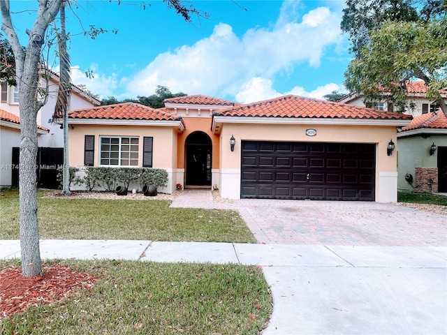 mediterranean / spanish-style house featuring a garage, a tiled roof, decorative driveway, stucco siding, and a front yard