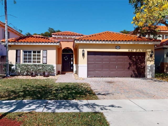 mediterranean / spanish-style house featuring a tiled roof, decorative driveway, an attached garage, and stucco siding