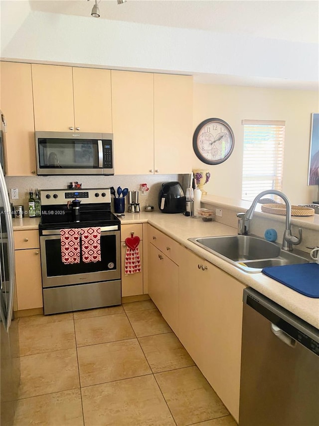 kitchen with light tile patterned floors, stainless steel appliances, tasteful backsplash, light countertops, and a sink