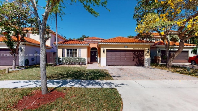 mediterranean / spanish house with a tile roof, an attached garage, decorative driveway, a front lawn, and stucco siding