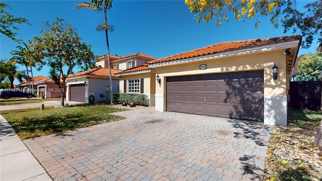 mediterranean / spanish home with a garage, decorative driveway, a tiled roof, and stucco siding
