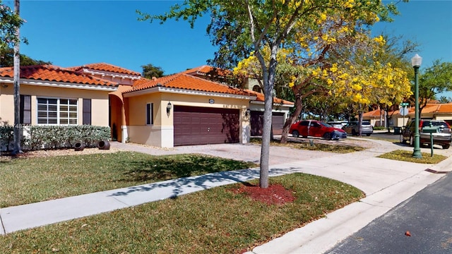 view of front of property with stucco siding, a front yard, a garage, driveway, and a tiled roof