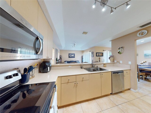 kitchen with a peninsula, appliances with stainless steel finishes, light countertops, and a sink