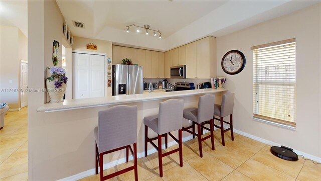 kitchen with a breakfast bar, cream cabinetry, light countertops, visible vents, and appliances with stainless steel finishes
