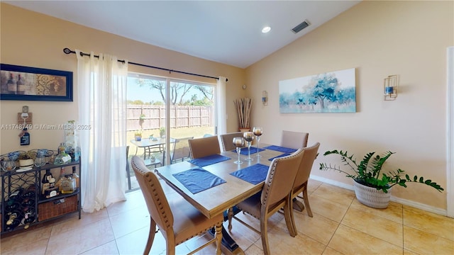 dining space with visible vents, vaulted ceiling, baseboards, and light tile patterned floors