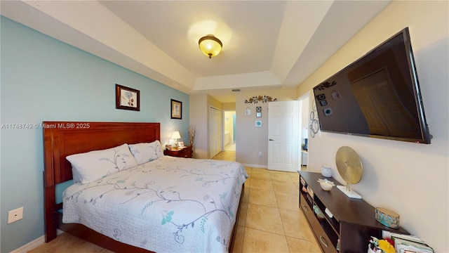 bedroom with a tray ceiling, light tile patterned flooring, and baseboards