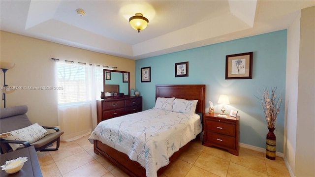 bedroom with light tile patterned floors, baseboards, and a tray ceiling