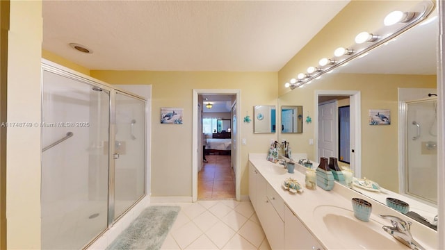 ensuite bathroom featuring double vanity, a stall shower, connected bathroom, a sink, and tile patterned flooring