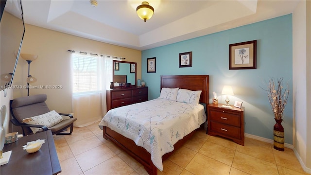 bedroom featuring baseboards, a tray ceiling, and light tile patterned flooring