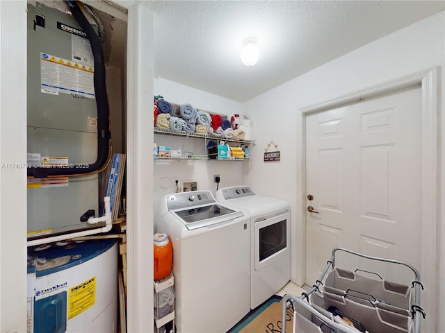 clothes washing area featuring a textured ceiling, laundry area, washer and clothes dryer, and heating unit