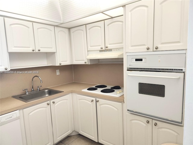 kitchen with white appliances, a sink, white cabinets, and under cabinet range hood