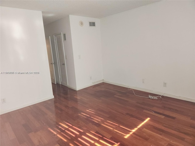 spare room featuring baseboards, visible vents, and dark wood-type flooring