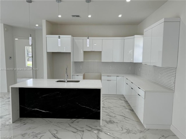 kitchen featuring white cabinets, decorative light fixtures, an island with sink, and modern cabinets