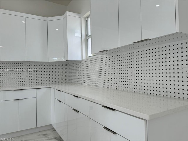 kitchen with marble finish floor, modern cabinets, white cabinetry, and decorative backsplash